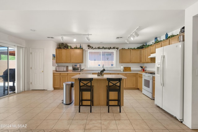 5897 E Cedarbird Dr, Tucson, AZ 85756 - kitchen featuring white appliances, light countertops, a kitchen island, under cabinet range hood, and a sink
