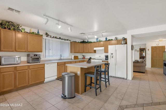 5897 E Cedarbird Dr, Tucson, AZ 85756 - kitchen featuring white appliances, under cabinet range hood, light countertops, a breakfast bar, and a kitchen island