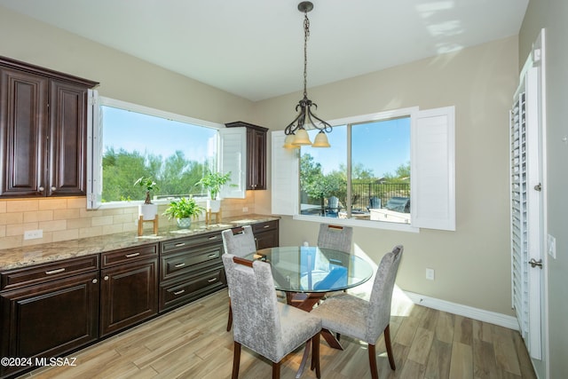 dining room featuring baseboards, light wood finished floors, and a healthy amount of sunlight