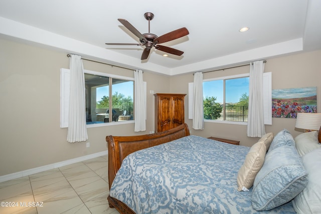 bedroom featuring baseboards, a raised ceiling, recessed lighting, and multiple windows