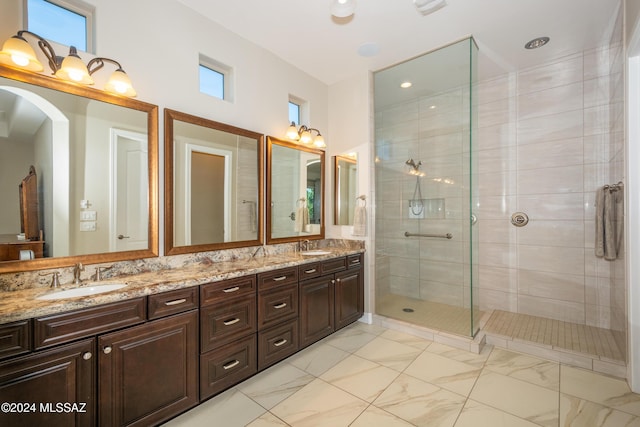 bathroom featuring marble finish floor, walk in shower, a sink, and double vanity