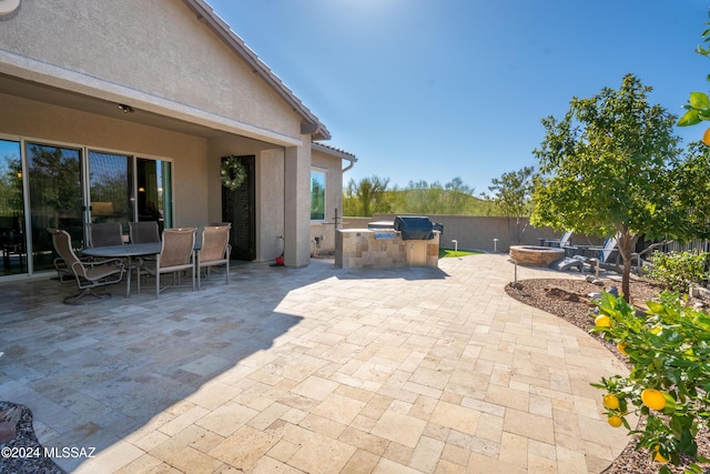 view of patio / terrace featuring fence, an outdoor kitchen, outdoor dining area, and a grill