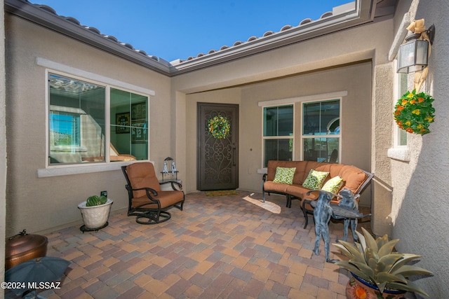 view of exterior entry with stucco siding and a patio