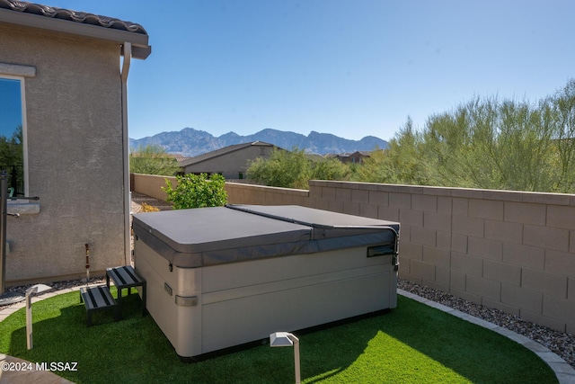 exterior space featuring a hot tub, fence, and a mountain view