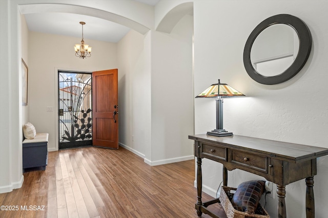 foyer featuring a notable chandelier, baseboards, and wood finished floors