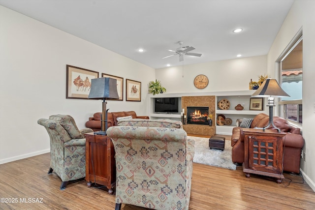 living area featuring light wood finished floors, a premium fireplace, recessed lighting, and baseboards