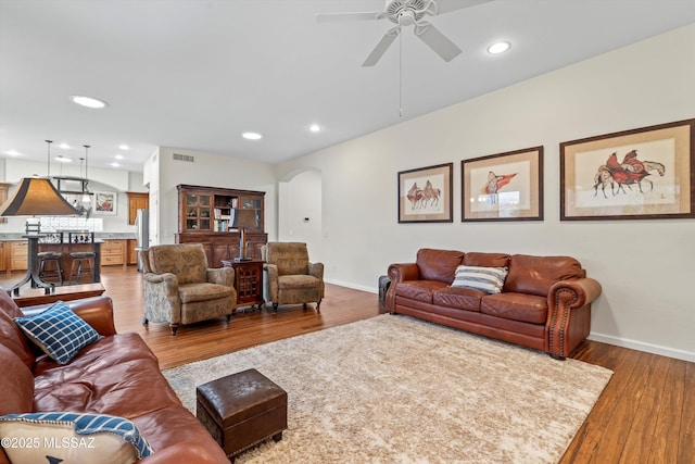 living area with baseboards, arched walkways, wood finished floors, and recessed lighting