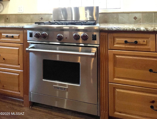 kitchen with brown cabinets, stainless steel range, and light stone countertops