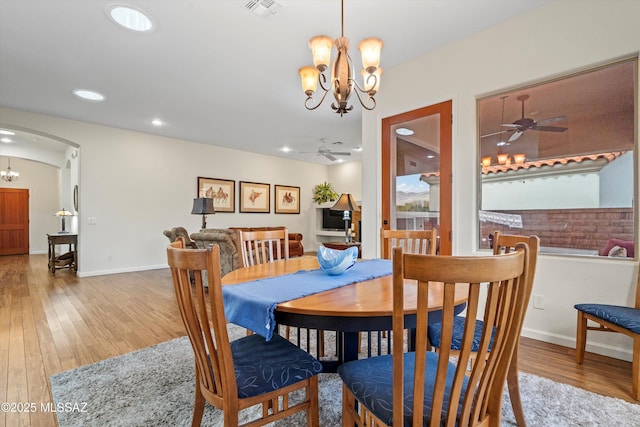 dining room featuring visible vents, arched walkways, wood finished floors, and ceiling fan with notable chandelier