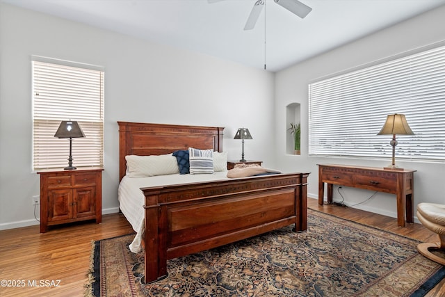 bedroom with multiple windows, light wood-type flooring, a ceiling fan, and baseboards