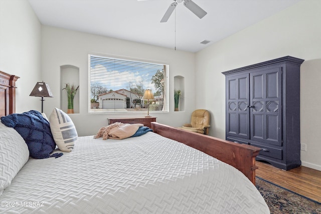 bedroom with ceiling fan, wood finished floors, visible vents, and baseboards