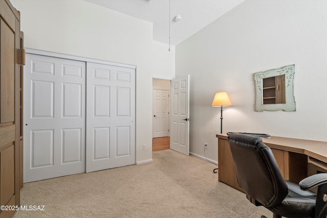 office area featuring baseboards, a high ceiling, and light colored carpet