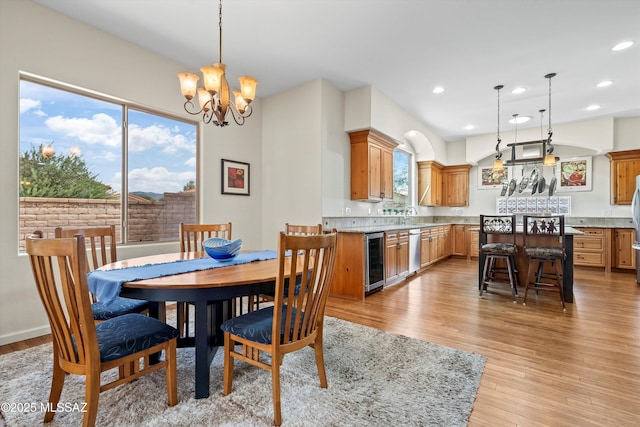 dining room with light wood-type flooring, a healthy amount of sunlight, beverage cooler, and recessed lighting