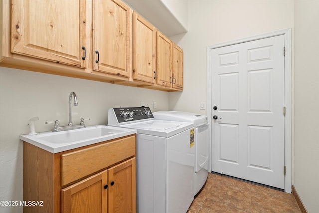 clothes washing area with cabinet space, washer and dryer, and a sink