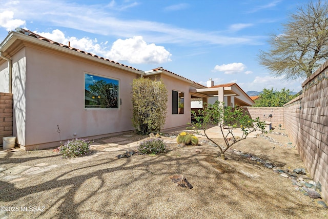 rear view of house featuring a tile roof, fence, a patio, and stucco siding