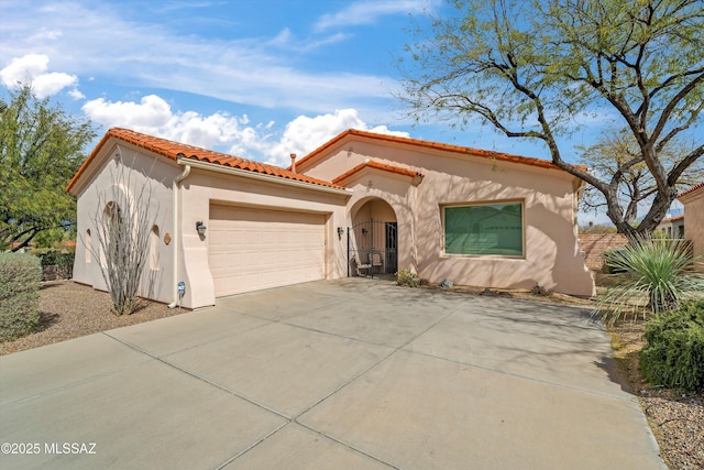 mediterranean / spanish house with a garage, a tile roof, concrete driveway, and stucco siding