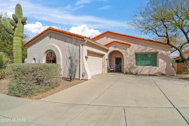 mediterranean / spanish-style house featuring an attached garage, stucco siding, driveway, and a tiled roof