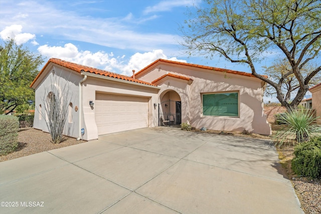 mediterranean / spanish-style house with concrete driveway, an attached garage, a tiled roof, and stucco siding