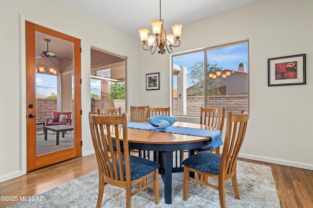 dining area with plenty of natural light, wood finished floors, an inviting chandelier, and baseboards