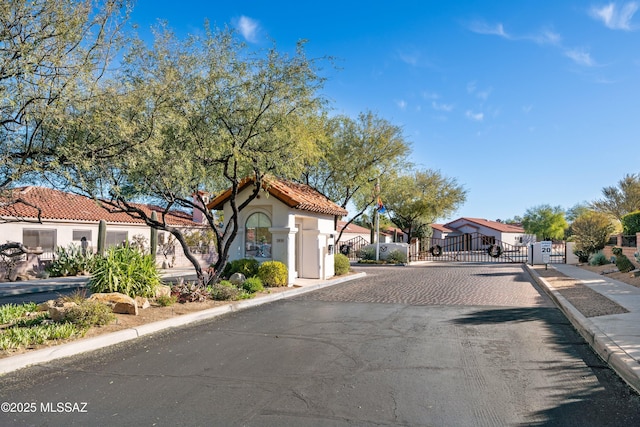 view of road featuring a gate, sidewalks, a gated entry, a residential view, and curbs