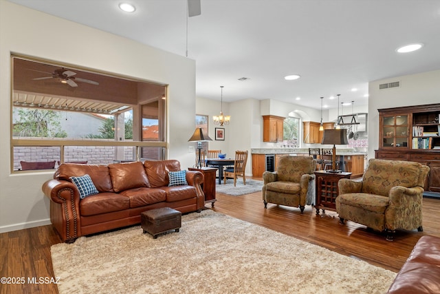 living area with recessed lighting, visible vents, wood finished floors, baseboards, and ceiling fan with notable chandelier