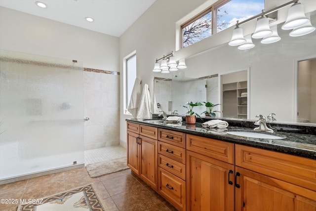 full bath with double vanity, tile patterned flooring, walk in shower, and a sink