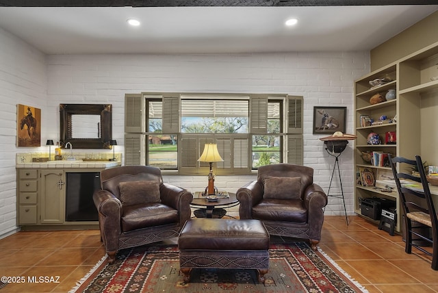 living area with brick wall, beverage cooler, and dark tile patterned flooring