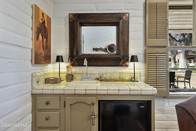 interior space with freestanding refrigerator, a sink, and tile countertops