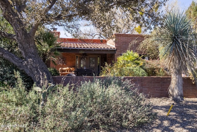 back of property with a tiled roof, a chimney, a patio area, and a ceiling fan