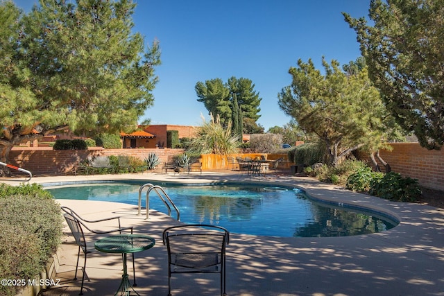 pool with a patio area and fence