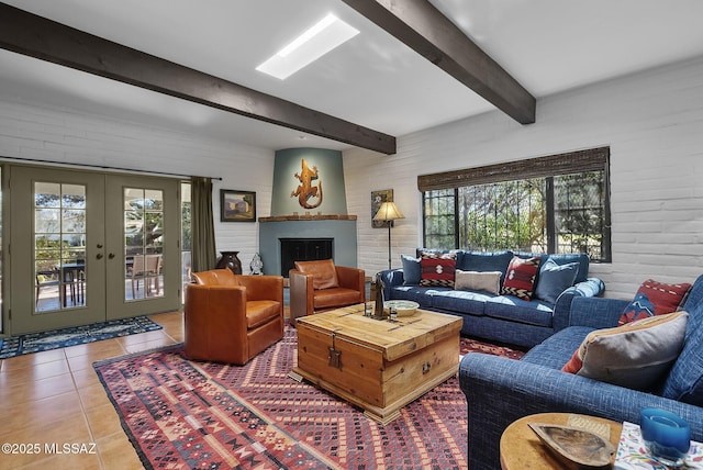 tiled living area with a large fireplace, beam ceiling, and french doors