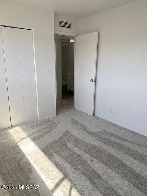 unfurnished bedroom with light colored carpet, a closet, and visible vents