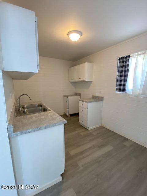 kitchen featuring white cabinets, light countertops, a sink, and wood finished floors