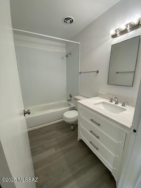 bathroom with visible vents, toilet, wood finished floors, tub / shower combination, and vanity