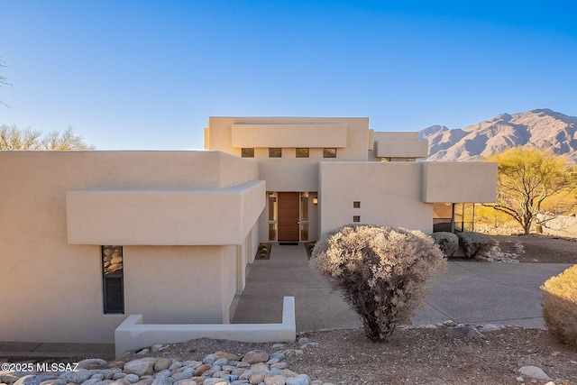 pueblo revival-style home featuring a mountain view and stucco siding