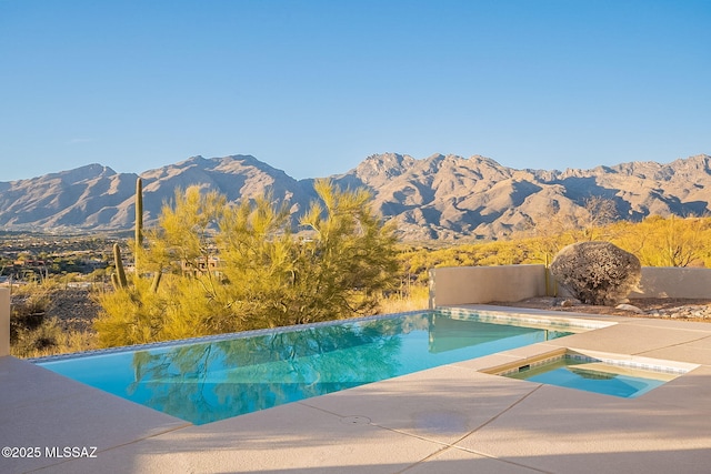 outdoor pool with a patio area, a mountain view, and an in ground hot tub