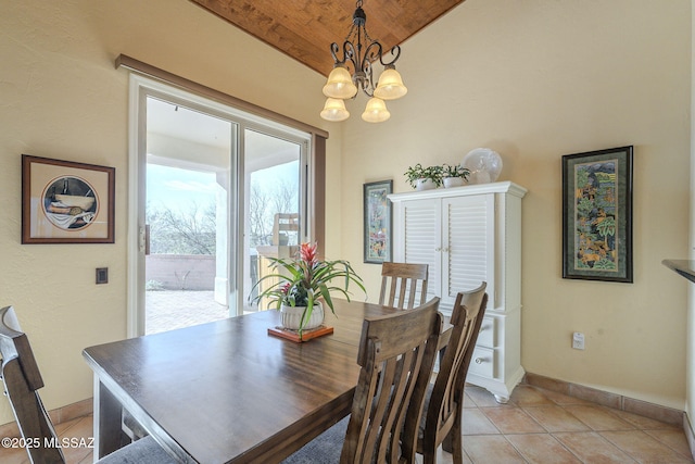 dining room featuring lofted ceiling, a notable chandelier, baseboards, and light tile patterned floors