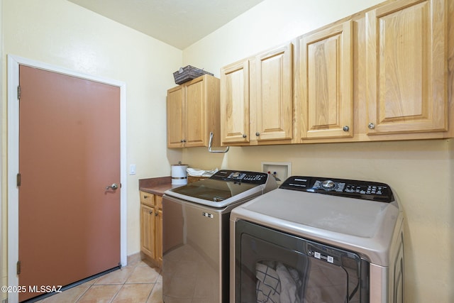 washroom with light tile patterned floors, independent washer and dryer, and cabinet space