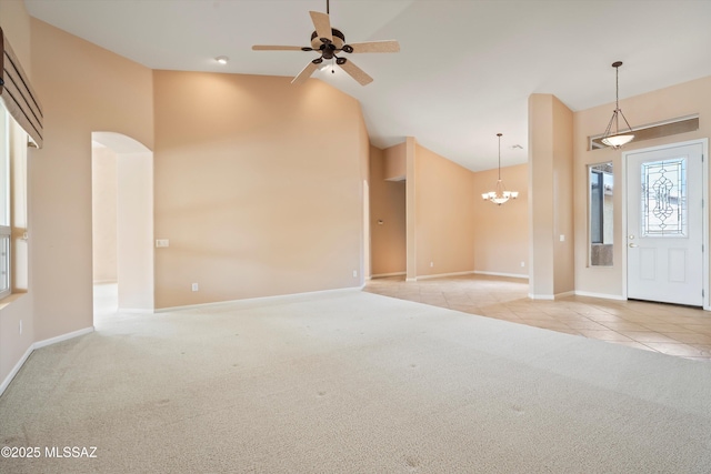 carpeted entryway with baseboards, ceiling fan with notable chandelier, high vaulted ceiling, and tile patterned floors