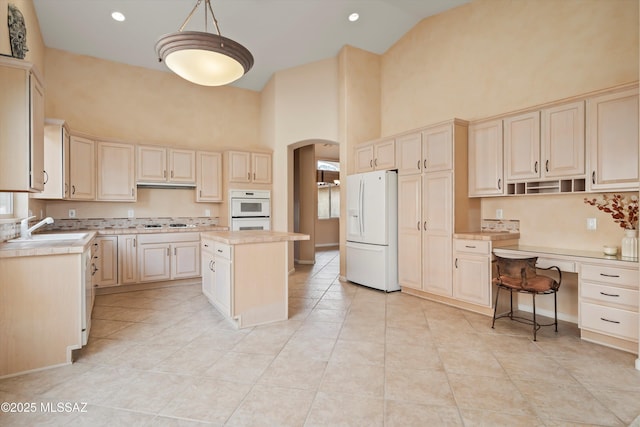 kitchen with white appliances, arched walkways, light countertops, high vaulted ceiling, and a sink