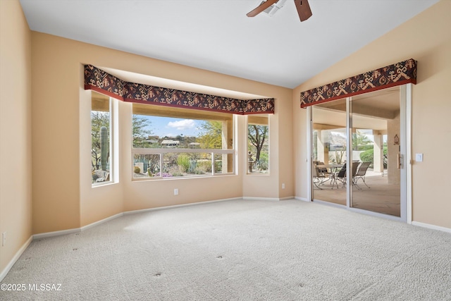 unfurnished room featuring lofted ceiling, carpet, a ceiling fan, and baseboards