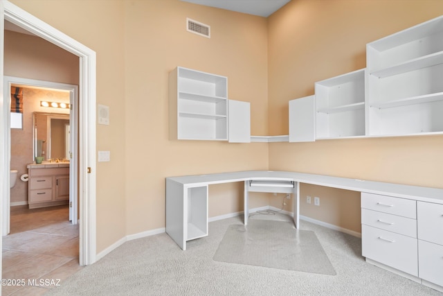 unfurnished office with light colored carpet, a sink, visible vents, baseboards, and built in study area