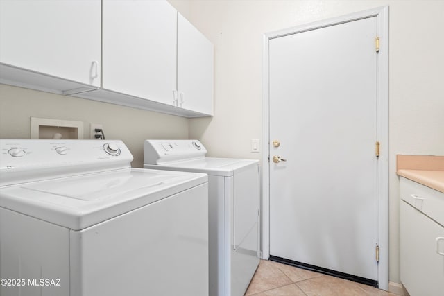 washroom featuring washer and dryer, cabinet space, and light tile patterned floors