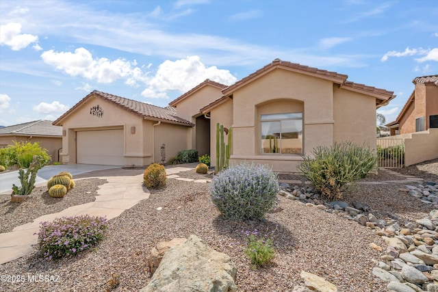 mediterranean / spanish house featuring stucco siding, concrete driveway, fence, a garage, and a tiled roof