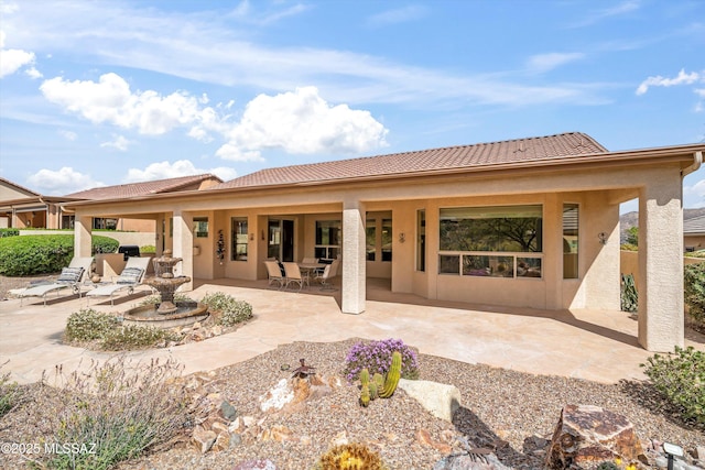 back of property with a patio area, a tile roof, and stucco siding