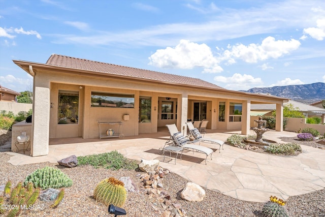 rear view of property featuring a patio area, fence, a mountain view, and stucco siding