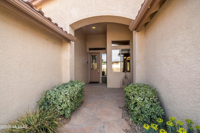 property entrance featuring a tile roof and stucco siding