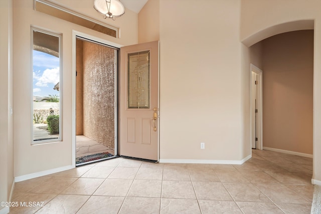 entryway with light tile patterned floors, baseboards, and arched walkways