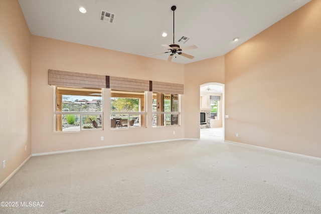 carpeted spare room with visible vents, baseboards, a ceiling fan, a fireplace, and recessed lighting