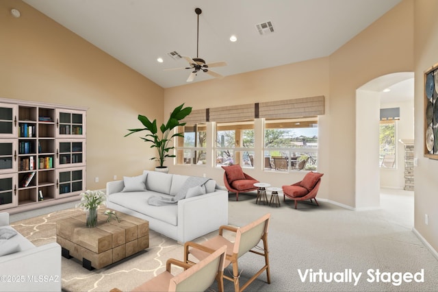 carpeted living room featuring high vaulted ceiling, visible vents, arched walkways, and recessed lighting